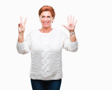 Gösterilen arka plan üzerinde kış kazak giyen Atrractive üst düzey beyaz Kızıl saçlı kadın izole ve parmakları ile işaret kendinden emin ve mutlu gülümseyerek süre yedi numara.