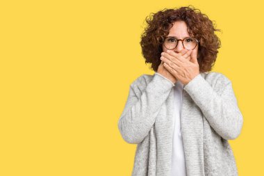 Güzel orta ager üst düzey kadın üzerine ceket ve gözlük takıyor arka plan ağız hata için elleriyle kapsayan şok izole. Gizli kavramı.