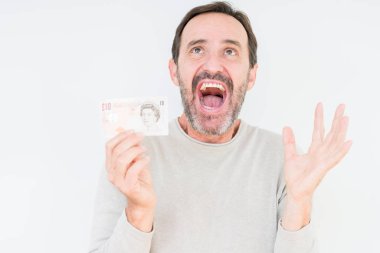 Komuta sizde 10 pound banknot büyük gülümseme ile çığlık zaferini kutluyor ve ellerini kaldırdı izole arka plan çok mutlu ve heyecanlı, kazanan ifade üzerinde tutan