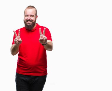 Zafer işareti yapıyor parmak gösterilen kamera seyir gülümseyen izole arka plan üzerinde kırmızı gömlek giymiş genç beyaz hipster adam. İki numaralı.