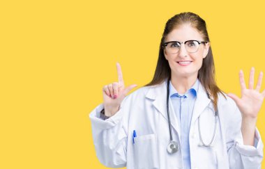 Gösterilen ve parmakları ile işaret izole arka plan üzerinde tıbbi ceket giyen orta yaş olgun doktor kadın kendinden emin ve mutlu gülümseyerek süre yedi numara.