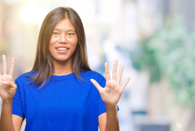 Genç Asyalı kadın gösterilen ve parmakları ile işaret izole arka plan üzerinde numara 9 kendinden emin ve mutlu gülümseyerek süre.