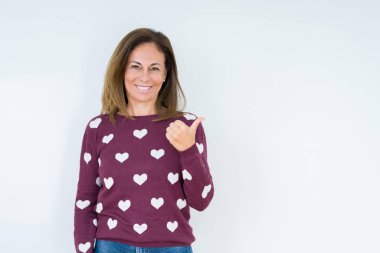 Hareketi el ile mutlu yaşasın yapıyor izole arka plan üzerinde kalp kazak giyen güzel orta yaş kadın. Başarı gösteren kameraya bakarak ifade onaylama.