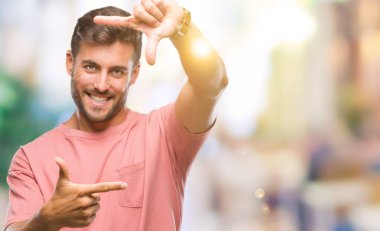 Yakışıklı delikanlı elle yapma çerçeve ve parmakları ile mutlu yüz gülümseyen izole arka plan üzerinde. Yaratıcılık ve Fotoğrafçılık kavramı.