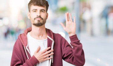 Yakışıklı delikanlı izole arka plan üzerinde göğüs ve bir sadakat sözü yemin yapma avuç, el ile küfür