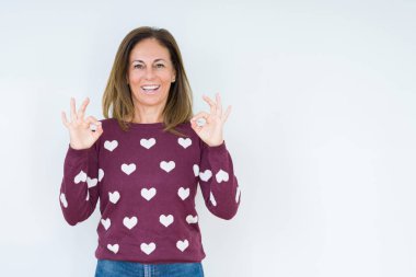Güzel orta yaş kadın giyiyor kalp kazak izole arka plan üzerinde dinlenmek ve gülümseyen gözlerle kapalı parmak jestle meditasyon yapıyor. Yoga kavramı.