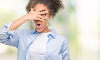 Yüz ve gözler el ile kapsayan şok bakmak izole arka plan üzerinde genç afro Amerikalı kadın mahcup ifadeyle parmaklarımın arasından arıyorsunuz.