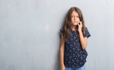 Genç İspanyol çocuk diş ağrısı veya dişlerde dişlerle ilgili hastalık nedeniyle ağız acı ifadesi ile el ile dokunmak grunge gri duvar için. Diş hekimi kavramı.