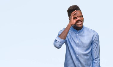 Genç Afro-Amerikalı iş adamı gülümseyen, parmakları ile mutlu yüz üzerinden seyir göz el ile ok jest yapıyor izole arka plan üzerinde.