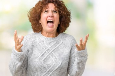 Üzerinde kış kazak giyen güzel orta ager üst düzey kadın arka plan deli izole ve deli bağırarak ve agresif ifade ve silah kaldırdı bağırıyor. Hayal kırıklığı kavramı.