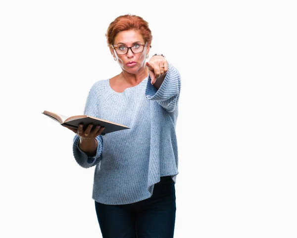 高级高加索妇女阅读一本书在孤立的背景手指指向相机和你 手的标志 积极和自信的手势从前面 — 图库照片