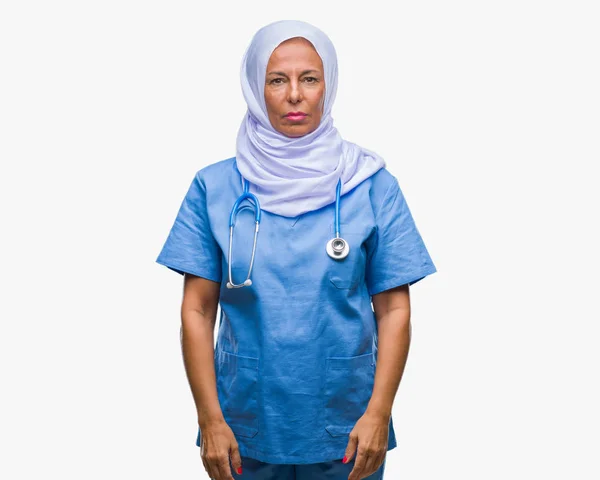 顔に真剣な表情で孤立した背景にヒジャーブを着て中年アラブに上級看護師の女性 シンプルで自然なカメラを見てください — ストック写真