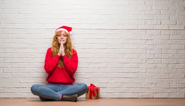 Молодая Рыжая Женщина Сидящая Кирпичной Стене Рождественской Шляпе Молится Руками — стоковое фото
