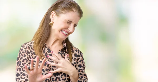 Beautiful middle age mature rich woman wearing leopard dress over isolated background disgusted expression, displeased and fearful doing disgust face because aversion reaction. With hands raised. Annoying concept.