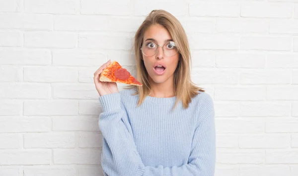 Mulher Bonita Sobre Parede Tijolo Branco Comendo Pizza Fatia Assustada — Fotografia de Stock