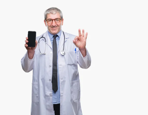 英俊的资深医生男子显示屏幕上的 Smarpthone 在孤立的背景做 符号与手指 优秀的符号 — 图库照片