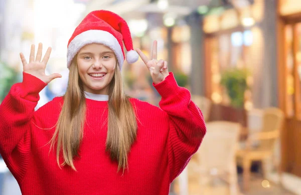 孤立した背景表示と指で上向きに身に着けているクリスマスの帽子を美しい若い女の子数は自信を持って 幸せな笑みを浮かべている間 — ストック写真