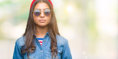 Genç güzel Arap kadın yüzünde ciddi bir ifade ile izole arka plan üzerinde güneş gözlüğü takıyor. Basit ve doğal kameraya bakıyor.