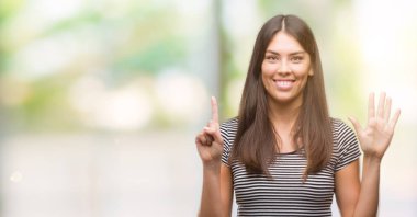 Gösterilen ve parmakları ile işaret genç güzel İspanyol kadın kendinden emin ve mutlu gülümseyerek süre 6 numara.