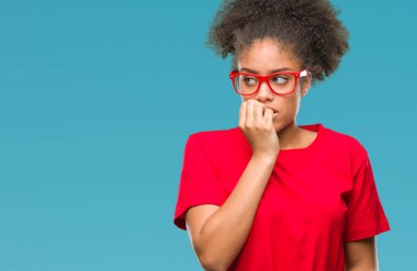 Stresli ve gergin elle çivi ısırma ağzına bakarak izole arka plan üzerinde gözlük takan genç afro Amerikalı kadın. Anksiyete sorunu.