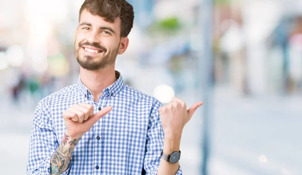 孤立した背景に若いハンサムな実業家自信の笑みを浮かべて手と親指 裏側を指す — ストック写真