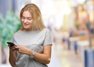 Beyaz kadın ayakta ve diş gösterilen kendine güvenen bir gülümsemeyle gülümseyerek mutlu bir yüz ile izole arka plan üzerinde Smartphone kullanarak ileti gönderme