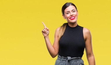 Kameraya bakarak yan el ve parmak ile işaret eden genç güzel şık iş kadını yüzünde kocaman bir gülümseme ile izole arka plan üzerinde.