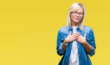 Genç güzel sarışın kadın ile gülümseyen izole arka plan üzerinde gözlük takan kapalı gözler ve yüzünde minnettar jest ile göğüs üzerinde eller. Sağlık kavramı.