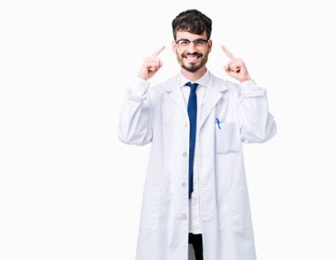 Beyaz önlük üzerinde izole giyen genç profesyonel bilim adam arka plan baş hem el parmak, harika bir fikir ya da düşünce, iyi bellek ile işaret eden gülen