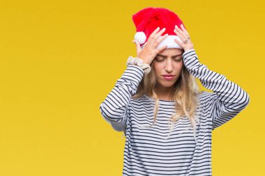 Çünkü çaresiz ve stresli baş ağrısı acı izole arka plan üzerinde Noel şapka giymiş güzel sarışın genç kadın acı ve migren. Ellerini kafasına.