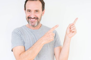 Gülümseyen ve iki elleri ve parmakları ile tarafına işaret kamera bakarak izole arka plan üzerinde üst düzey yakışıklı.