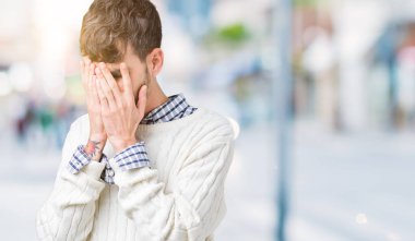 Genç yakışıklı adam üzgün ifade yüz eller ile ağlayarak süre kapsayan ile izole arka plan üzerinde kış kazak giyiyor. Depresyon kavramı.