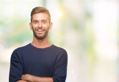 Mutlu yüz ile gülümseyerek kameraya seyir silah geçti arka plan üzerinde kış kazak giyen genç yakışıklı adam izole. Olumlu bir kişi.