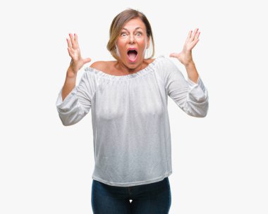 Orta yaş üst düzey İspanyol kadın deli kutluyor arka plan izole ve başarı için kaldırdı kollarını açarak hayrete ve heyecanlı çığlık gözleri açık. Kazanan kavramı