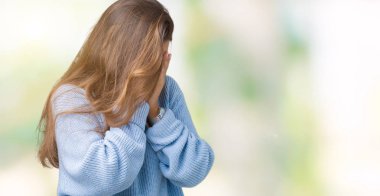 Yüzünü elleriyle ağlayarak süre kapsayan üzgün ifade ile izole arka plan üzerinde mavi kış kazak giyen genç güzel esmer kadın. Depresyon kavramı.