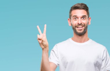 Mutlu yüz zafer işareti yaparken kameraya göz kırpıyor ile gülümseyen izole arka plan üzerinde genç yakışıklı adam. İki numaralı.
