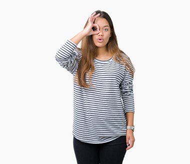 Sürpriz yüz, göz parmaklarının arasından seyir ile ok jest yapıyor izole arka plan üzerinde çizgili süveter giyen genç güzel esmer kadın şok. İmansız ifade.