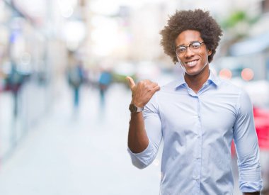 Seyir ve başparmak yanında yukarıyı mutlu yüz ile gülümseyen izole arka plan üzerinde gözlük takan Afro Amerikalı iş adamı.