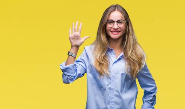 Genç güzel sarışın iş kadın gözlük gösterilen ve parmakları ile işaret izole arka plan üzerinde kendinden emin ve mutlu gülümseyerek süre 5 numara.