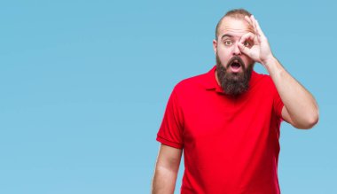 Sürpriz yüz, göz parmaklarının arasından seyir ile ok jest yapıyor izole arka plan üzerinde kırmızı gömlek giymiş genç beyaz hipster adam şok. İmansız ifade.