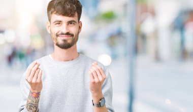 Maaş ödeme için milyoner iş soran izole arka plan yapıyor para hareketi el ile üzerinden sweatshirt giyen genç yakışıklı adam