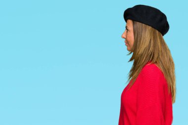 Orta yaş yetişkin kadın giyiyor moda bere izole arka tarafına, seyir üzerinde dinlenmek doğal yüz emin gülümseme ile pozuyla profili.