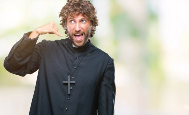 Yakışıklı İspanyol Katolik rahip adam yapıyor gülümseyen izole arka plan üzerinde telefon hareketi ile el ve parmak telefonda konuşuyor gibi. Kavramları iletişim.