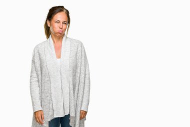 Komik surat ile yanakları şişirme izole arka plan üzerinde kış kazak giyen güzel orta yaş yetişkin kadın. Ağız ile hava, deli ifade şişirilmiş.