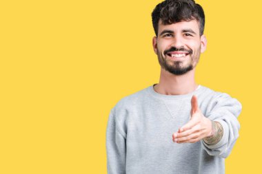 Yakışıklı genç dostu sunan karşılıklı tebrik ve davet edici gülümseyen izole arka plan üzerinde kazak giyiyor. Başarılı iş.