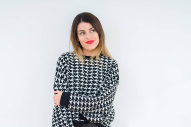 Görünümlü yan ve dik dik bakma uzağa düşünce gülümseyen izole arka plan üzerinde rahat kazak giyen genç kadın.