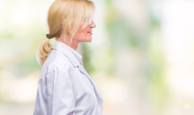 Tarafına, seyir izole arka plan üzerinde beyaz önlük giyen orta yaş sarışın terapist kadın dinlenmek doğal yüz emin gülümseme ile pozuyla profili.