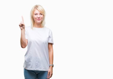 Ve kendinden emin ve mutlu gülümseyerek süre parmak numaralı yukarıyı gösteren izole arka plan üzerinde beyaz t-shirt giyen genç güzel sarışın kadın.