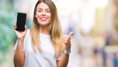 Genç güzel kadın gösteren boş ekran smartphone işaret ve başparmak kadar mutlu yüz gülümseyen tarafı ile gösteren izole arka plan üzerinde