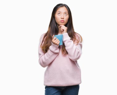 Genç Asyalı kadın izole arka plan ciddi bir yüz düşünme hakkında soru, çok karışık bir fikir üzerinde kahve içme